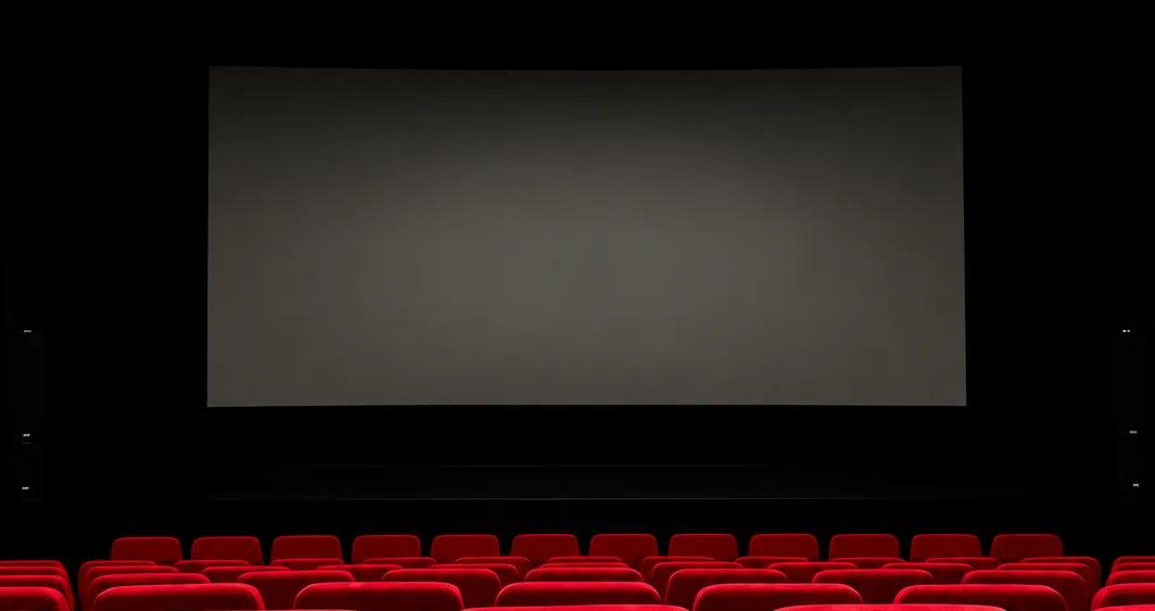 Grand écran de cinéma face aux rangées de fauteuils rouges